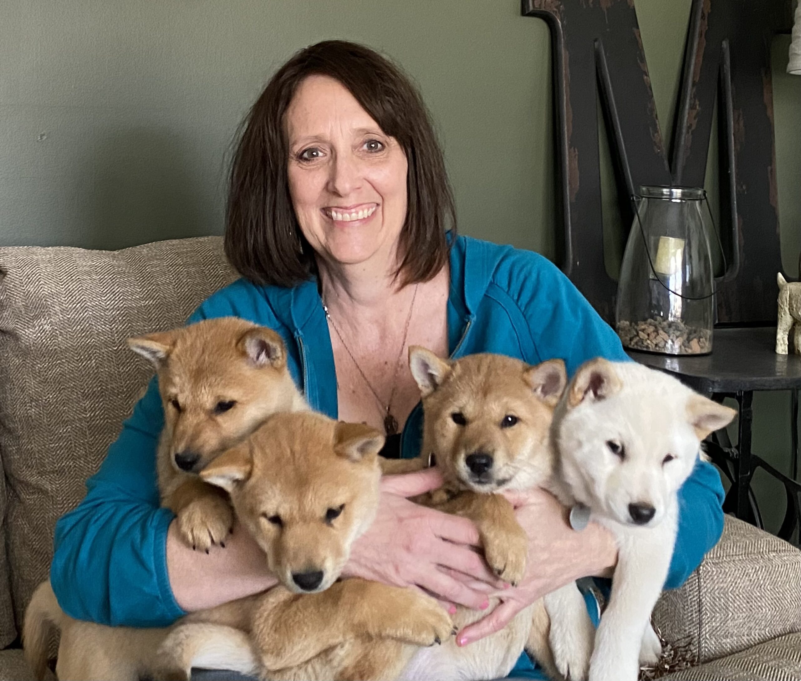 Mary Hager holding four shiba inu puppies.