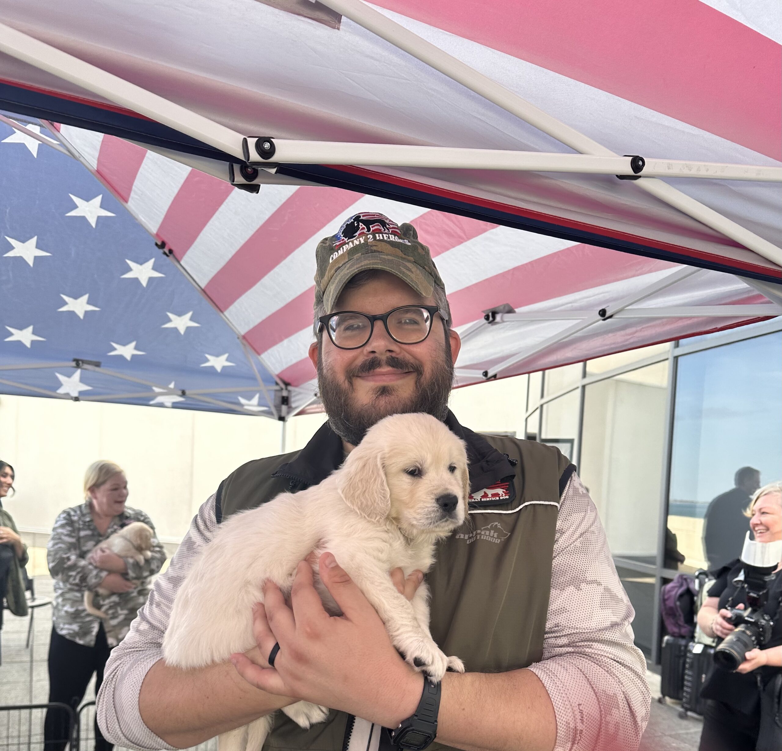 Man smiling holding a golden retriever pup