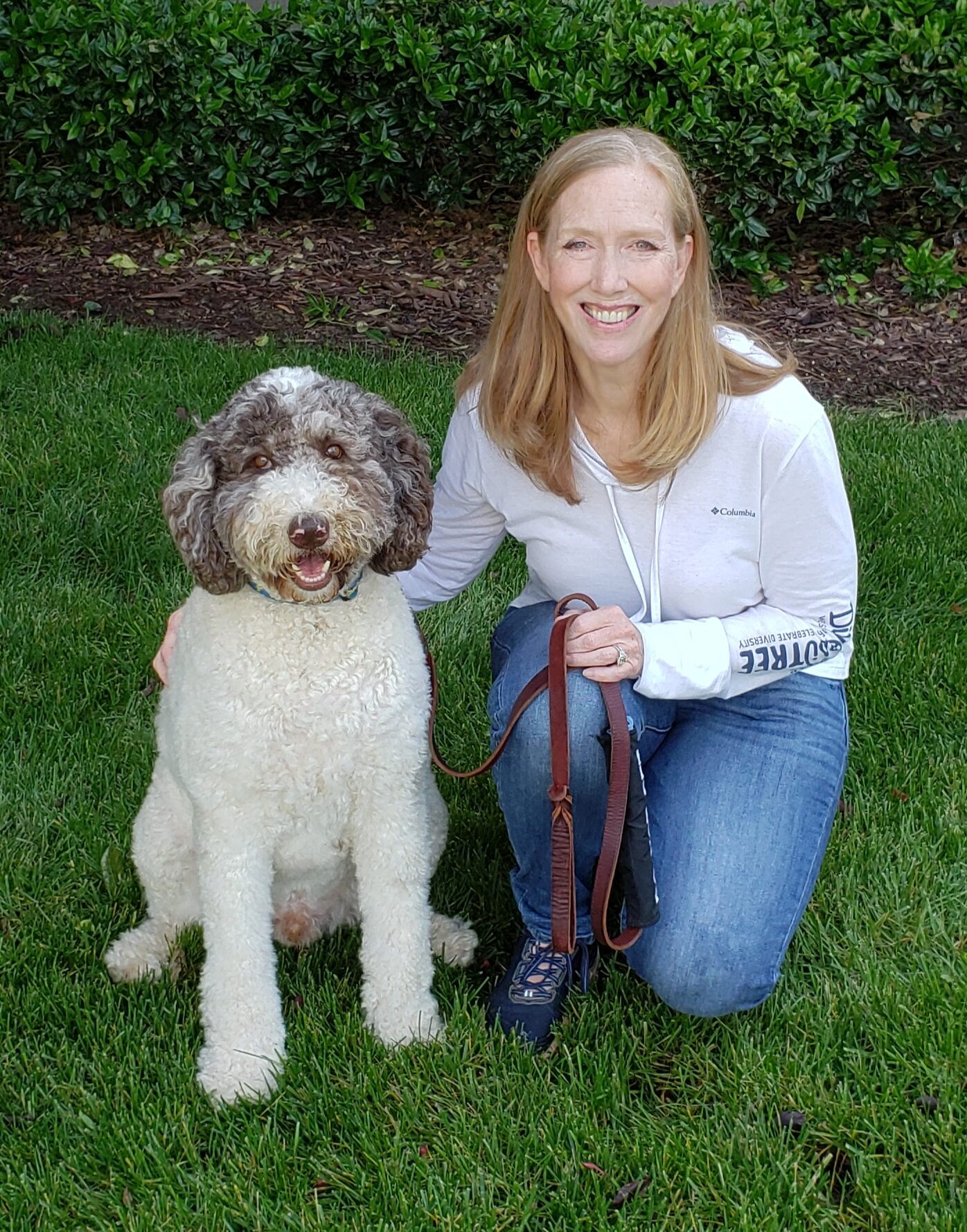 Jeanne Hodson, woman smilling next to labradoodle